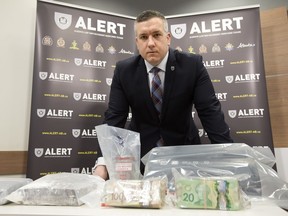 RCMP Staff Sgt. Dave Knibbs poses in February with some of the cocaine and money seized following the Alberta Law Enforcement Response Teams' arrest of  Hells Angels member Dominic DiPalma Jr.