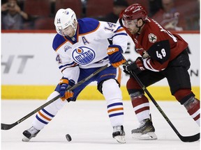 Edmonton Oilers' Jordan Eberle (14) tries to control the puck in front of Arizona Coyotes' Jordan Martinook (48) during the first period of an NHL hockey game, Tuesday, March 22, 2016, in Glendale, Ariz.