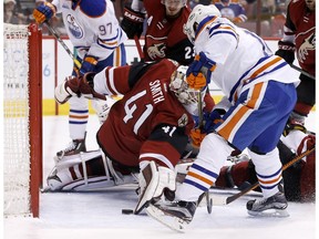 The puck gets past Arizona Coyotes' Mike Smith (41) as Edmonton Oilers' Jordan Eberle, middle, gets ready to score as Oilers' Nail Yakupov, right, of Russia, looks on during the first period of an NHL hockey game, Tuesday, March 22, 2016, in Glendale, Ariz.