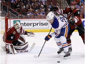 Edmonton Oilers' Connor McDavid (97) tries to get control of the puck as he gets shoved by Arizona Coyotes' Oliver Ekman-Larsson, right, of Sweden, as Coyotes goalie Mike Smith watches during the first period of an NHL hockey game Tuesday, March 22, 2016, in Glendale, Ariz. The Coyotes won 4-2.