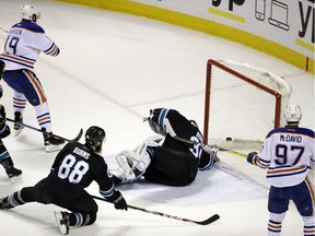 Edmonton Oilers' Patrick Maroon, top left, scores past San Jose Sharks goalie James Reimer, center, during the second period of an NHL hockey game Thursday, March 24, 2016, in San Jose, Calif.