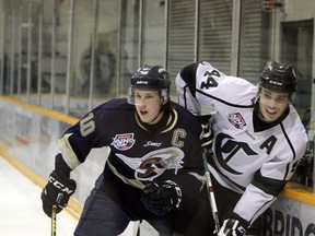 Sherwood Park Crusaders left-wing Devon McAndrews and Spruce Grove Saints captain Tyler Busch tangle along the boards during Wednesday's AJHL playoff game in Sherwood Park.