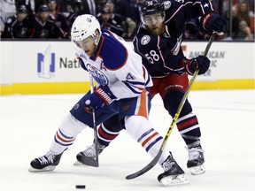 Edmonton Oilers' Taylor Hall, left, and Columbus Blue Jackets' David Savard work for the puck during the first period of an NHL hockey game in Columbus, Ohio, Friday, March 4, 2016.