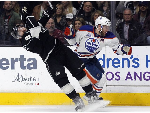 Edmonton Oilers left wing Taylor Hall, right, knocks back Los Angeles Kings defenseman Drew Doughty in pursuit of the puck during the first period of an NHL hockey game in Los Angeles, Saturday, March 26, 2016.