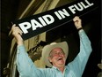 Alberta Premier Ralph Klein holds up a "Paid in Full" sign in 2004 after announcing that the province's debt of $3.7-billion has been paid off in full ahead of schedule. Paige MacPherson writes Klein's approach was the right strategy for the province as it struggled with debt, a lesson that could be applied today.