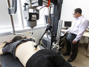 Lead engineer Anthony Au (right) demonstrates a vibration test during a press conference at the Edmonton Clinic Health Academy at the University of Alberta in Edmonton, Alta., on Thursday March 10, 2016. Using an identical twin study from the University of Southern Denmark, the team shows that structural changes within the spine alter its vibration response significantly. Their research is being published online in Nature: Scientific Reports. (Publication embargoed until March 11 at 3am) Photo by Ian Kucerak