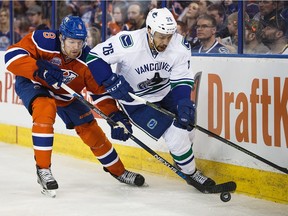 Edmonton Oilers defenceman Griffin Reinhart battles along the boards against Vancouver Canucks' Emerson Etem on the way to a 2-0 Oilers win at Rexall Place Friday. (Codie McLachlan/Getty Images)