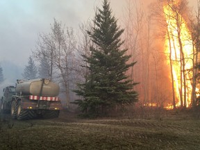 A water truck fights a brush fire near Edmonton on Tuesday, April 19, 2016. Grass and brush fires forced people from their homes in some small communities in Alberta Tuesday as dry conditions and hot temperatures pushed the danger to as high as extreme.