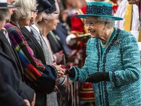 Queen Elizabeth II (R) distributes Maundy money during the Royal Maundy Service at St George's Chapel in Windsor, west of London, on March 24, 2016. The Queen, who turns 90 on April 21, distributed the Maundy money to 90 men and 90 women — one for each of her 90 years.