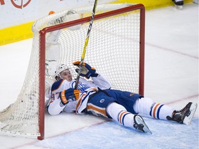 Edmonton Oilers' Connor McDavid slides into the back of the Vancouver Canucks net after being upended by Canucks' Nikita Tryamkin, of Russia, during the second period of an NHL hockey game in Vancouver, B.C., on Saturday April 9, 2016.