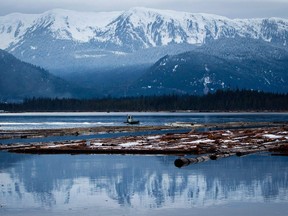 A worker uses a small boat to move logs on the Douglas Channel at dusk in Kitimat, B.C., in 2012. The channel is the planned termination point for an for an oil pipeline from Alberta as part of the Enbridge Northern Gateway Project. Using the pipeline to move synthetic crude oil, instead of bitumen, could improve buy-in for the project, writes Paul Precht.