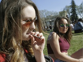 Two women smoke a joint at the Edmonton 4-20 marijuana rally on the Alberta legislature grounds in Edmonton on April 20, 2016.