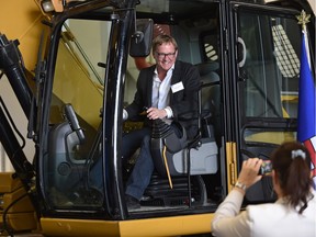 David Eggen, Minister of Education, poses for a photo in an excavator at the official opening of NAIT's new Heavy Equipment Technology Building.