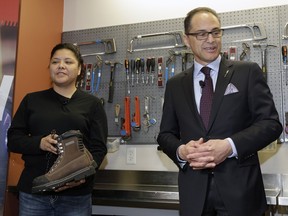 Alberta Finance Minister Joe Ceci donates work boots to Women Building Futures student Kim Brertton during a media event Wednesday in Edmonton.