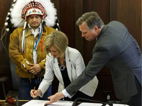 Deputy Grand Chief Isaac Laboucan-Avirom (left), Premier Rachel Notley (centre) and Indigenous Relations Minister Richard Feehan sign a protocol agreement between the Government of Alberta and Treaty 8 First Nations at the Alberta legislature Tuesday April 26, 2016.
