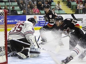 Jackson Houck of the Calgary Hitmen slips a puck through the pads of Red Deer Rebels goaltender Trevor Martin during Game 5 action at the Enmax Centrium in Red Deer, Alta., on April 2, 2016.