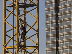 A man climbs down from a construction crane in the arena district, near 102 Street and 103 Avenue, on Sunday. He was fined.