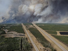 This May 5, 2016, image released by the Canadian National Defence shows an aerial view of highway 63 as smoke from fires billows south of Fort McMurray, taken from a CH-146 Griffon helicopter.