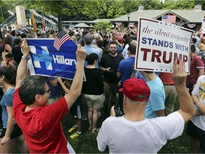 A supporter of Democratic presidential candidate Hillary Clinton and a Republican presidential candidate Donald Trump supporter hold signs as they attend a Memorial Day parade on May 30, 2016, in Chappaqua, N.Y.