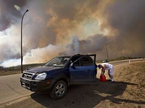 An evacuee puts gas in his car on his way out of Fort McMurray on Wednesday May 4, 2016. The wildfire has already torched 1,600 structures in the evacuated oil hub of Fort McMurray and is poised to renew its attack in another day of scorching heat and strong winds.