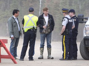 Alberta Wildrose Leader Brian Jean, centre, talks with police near a wildfire in Fort McMurray on May 5, 2016. Jean's home was one of the hundreds destroyed in the fire.