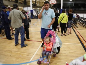 Evacuee from the Fort McMurray wildfires, Chance Jones, an employee of CNRL, talks on a cell phone while looking after his daughter at the evacuation centre in Lac la Biche, Alta., Thursday, May 5, 2016.