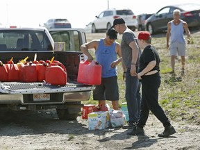 ordan Ladoucheur (left), from the Kikino Metis Settlement, helps evacuees from Fort McMurray, Alberta by distributing free gas, food and diapers to evacuees southbound on Highway 63.