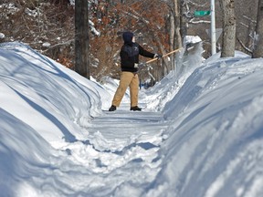 A man shovels his Edmonton sidewalk after a March 2013 snowstorm dropped at least 25 centimetres of snow on the city.