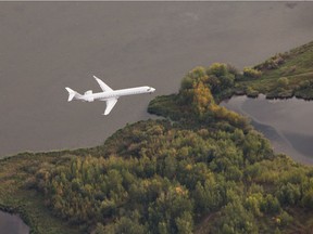 An airplane flies over a small lake as it comes in for landing near Edmonton International Airport on September 2, 2015. More foreign tourists are being lured to the province by the low dollar.