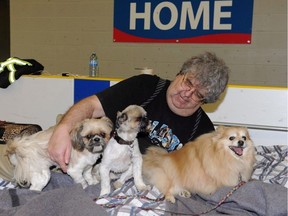Dale Kossey with his three dogs Elmo, Gizmo, and Lacey rests in an area for pet owners in the reception centre at an evacuee reception centre set up and operated by the Regional Municipality of Wood Buffalo in nearby Anzac, on Wednesday, May 4, 2016.