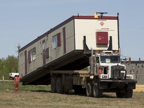 A worker guides a portable home into place which will serve as relief accommodations for evacuees from Fort Mcmurray and service workers that have come to the Lac La Biche area on May 6, 2016.
