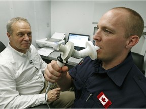 Strathcona County firefighter Jason Biggeman (right) blows into a spirometer to test his lung function after returning from fighting the forest fire in Fort McMurray. Professor Jeremy Beach (left, Dept. of Medicine, University of Alberta) was part of a team conducting the tests on the firefighters.
