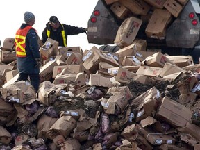 A Canada Food Inspection Agency employee, left, looks on as beef from the XL Foods cattle processing plant is dumped at a landfill site near Brooks in 2012.
