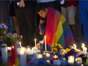 A man, wrapped in a Rainbow Flag, lights a candle during a vigil in Washington, D.C., on June 13, 2016, hosted by the Muslim American Women's Policy Forum, in memory of the victims of the Orlando mass shooting. A gunman opened fire inside a crowded gay nightclub early Sunday, before dying in a gunfight with SWAT officers, police said.