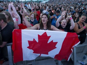 Fans sing the national anthem during the Fire Aid for Fort McMurray concert at Edmonton's Commonwealth Stadium on June 29, 2016.
