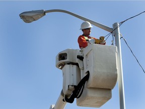 Joel Kwasny works to put in temporary overhead power to a light standard near the corner of 106A avenue and 65 Street. Upgrading light standards is a key part of Edmonton's plan to reduce greenhouse gas emissions.