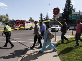 Community members cross the road as Edmonton Police Service officers investigate after a male pedestrian was killed in a hit and run at 48 Street and Mill Woods Road South in Edmonton on Monday June 20, 2016.