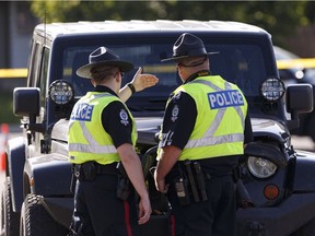 Edmonton Police Service officers investigate near a Jeep at 37 Street and 12A Avenue after a male pedestrian was killed in a hit and run at 48 Street and Mill Woods Road South in Edmonton, Alta., on Monday June 20, 2016.  Photo by Ian Kucerak