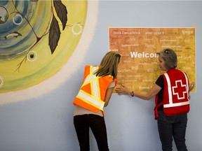 Sarah Thomas from the Regional Municipality of Wood Buffalo and Becky Row with the Red Cross hang a welcome sign as they get ready to open the door at the Nistawoyou Association Friendship Centre on June, 3 2016 in Fort McMurray.