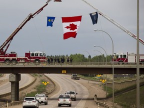 Firefighters and RCMP officers wave at motorists as they enter Fort McMurray on June, 1 2016 as 15,000 residents re-enter the city almost a month after an out-of-control wildfire forced them to flee their homes.