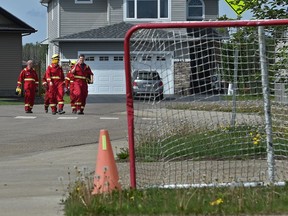 A crew of firefighters from Calgary walking up a street in the northend of the Timberlea area in Fort McMurray, after checking for hot spots along a fire guard behind the homes, June 2, 2016.
