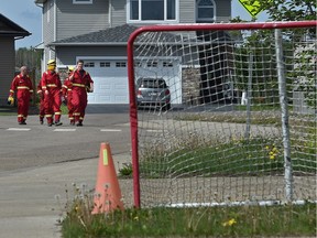 A crew of firefighters from Calgary walking up a street in the north end of the Timberlea area in Fort McMurray, after checking for hot spots along a fire guard behind the homes on June 2, 2016.
