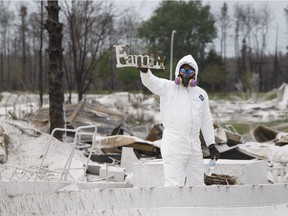Terry Brittain finds a beloved family item while wearing personal protective equipment in the Beacon Hill neighbourhood in Fort McMurray, Alta., on Wednesday June 8, 2016.