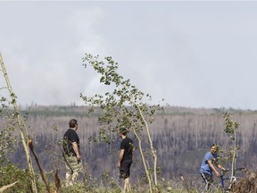 Residents watch as water bombers work near a flame-up east of Fort McMurray on June 6, 2016. Smoke from fires in the Northwest Territories is blowing through northern Alberta but there are no active wildfires in the vicinity of Fort McMurray, officials say.