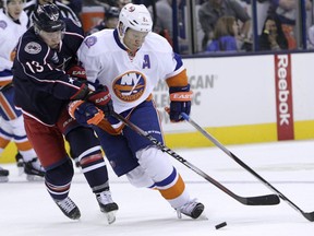 New York Islanders' Kyle Okposo, right, carries the puck up ice as Columbus Blue Jackets' Cam Atkinson defends during the third period of an NHL hockey game Saturday, Jan. 10, 2015, in Columbus, Ohio. The Islanders beat the Blue Jackets 5-2.