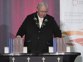 Justice Murray Sinclair pauses and places his hands on the final report of the Truth and Reconciliation commission following its unveiling, on December 15, 2015, in Ottawa. The report included many recommendations tied to education.