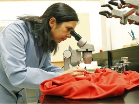 Rachel McQueen examines clothing in the lab at the University of Alberta in Edmonton on Wednesday June 22, 2016.