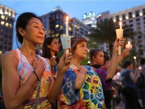 Sam Jitaree, left, and Devi Thompson of Orlando, Fla., hold candles at a vigil for the victims of a mass shooting at the Pulse nightclub, at Dr. Phillips Performing Arts Center in downtown Orlando on June 13, 2016.