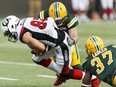Ottawa's Greg Ellingson (82) is tackled by Edmonton's Kenny Ladler (37) and an unidentified Eskimos defender during CFL action between the Edmonton Eskimos and the Ottawa Redblacks at The Brick Field at Commonwealth Stadium on June 25, 2016.