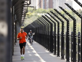 A runner crosses the west sidewalk of the High Level Bridge, with a cyclist coming up behind on his left.